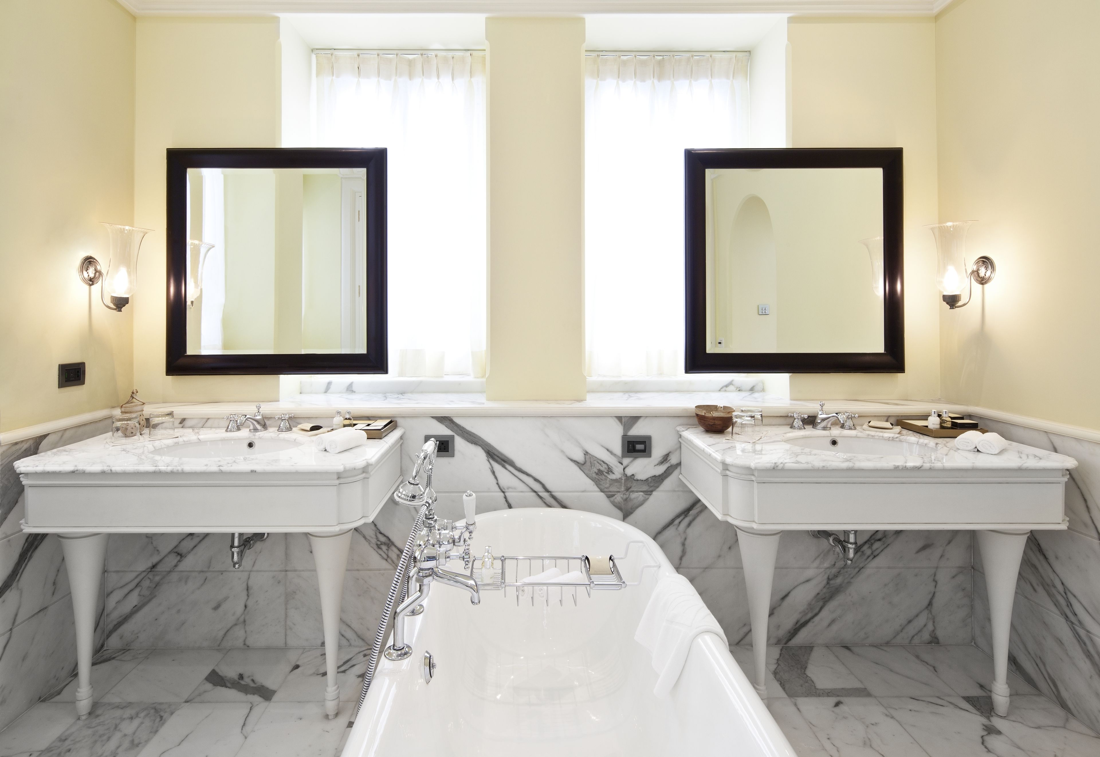 A bathroom with two sinks, a bathtub, and two large mirrors.