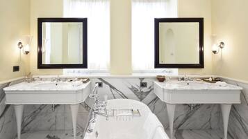 A bathroom with two sinks, a bathtub, and two large mirrors.