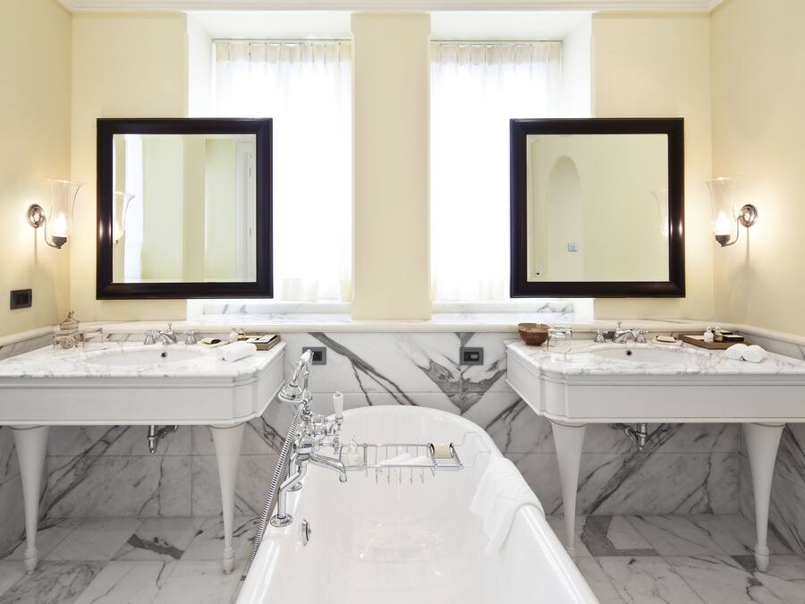 A bathroom with two sinks, a bathtub, and two large mirrors.