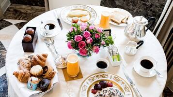A breakfast table with pastries, coffee, juice, and a bouquet of flowers.