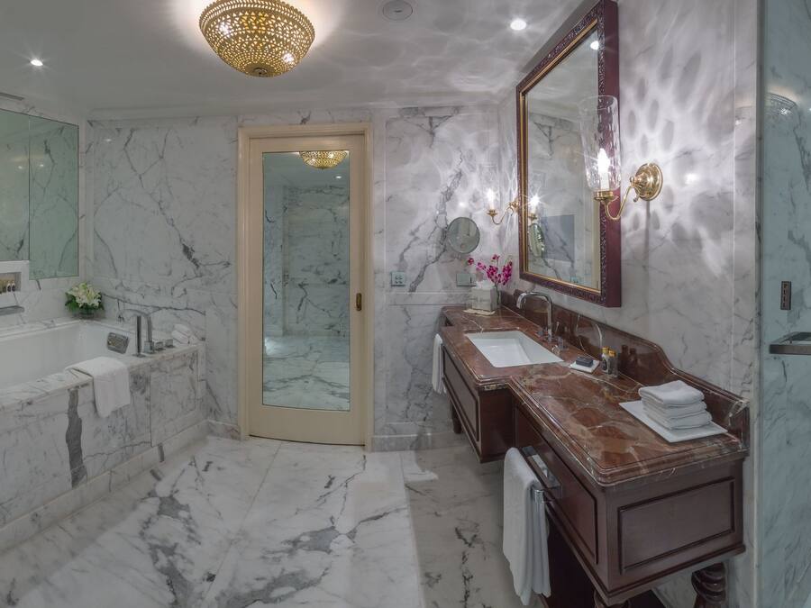 A modern bathroom with a marble floor, a bathtub, a double sink vanity, a large mirror, and a shower area.