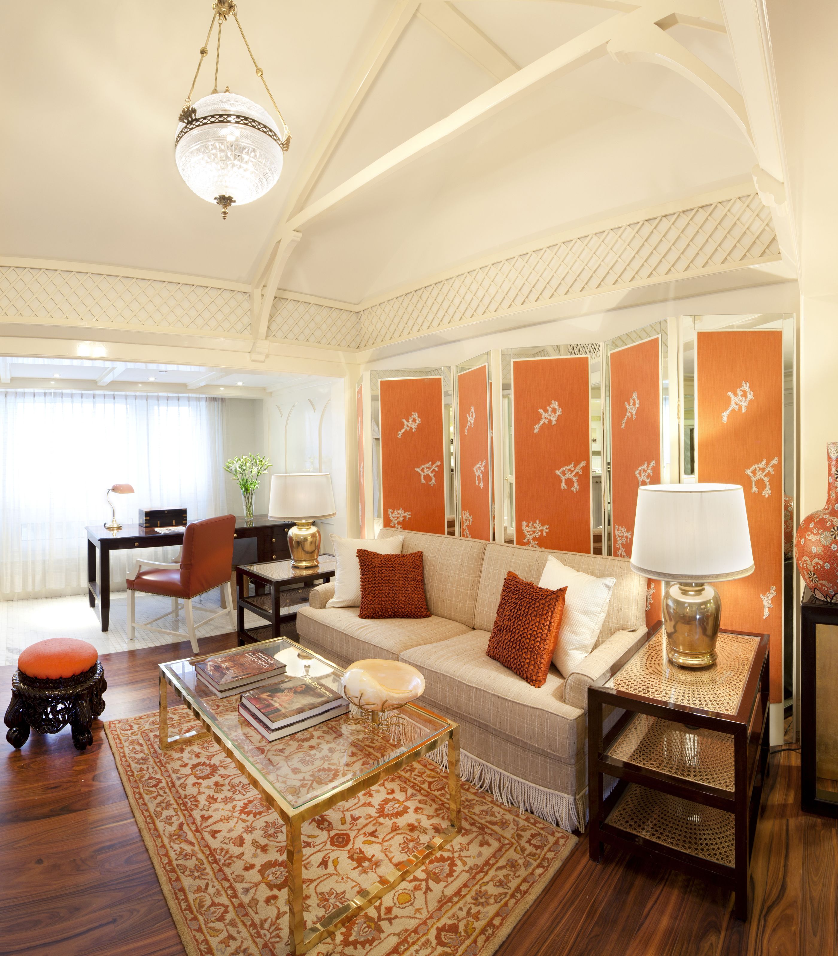 A spacious living room with a high ceiling, a large sofa, a coffee table, and a dining area with a table and chairs.