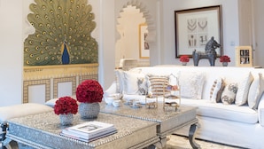 A luxurious living room with a white sofa, a decorative peacock mirror, and a chandelier. - The Taj Mahal Palace Mumbai (Mumbai)