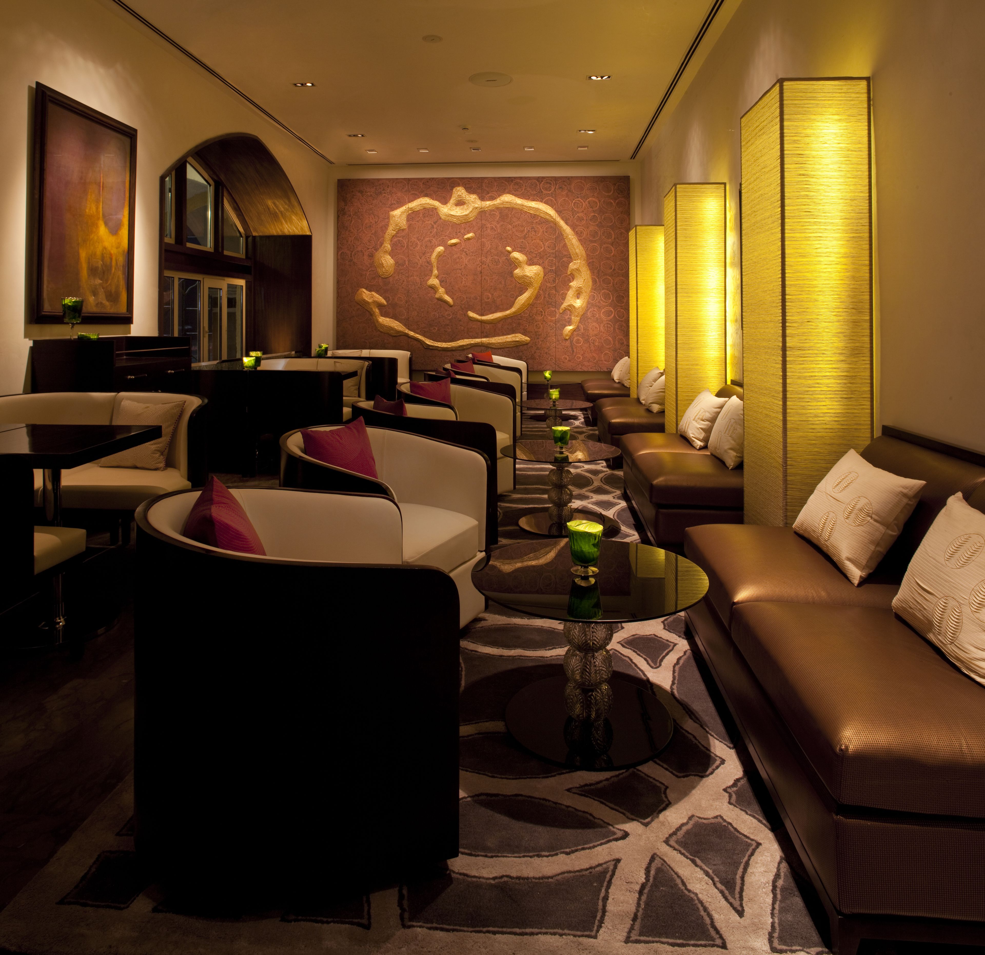 A modern lounge area with leather sofas, round tables, and ambient lighting.