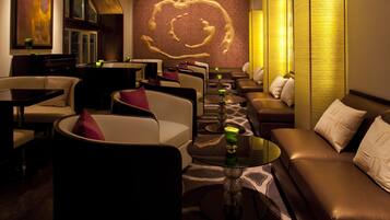 A modern lounge area with leather sofas, round tables, and ambient lighting.