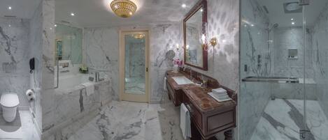 A modern bathroom with a marble floor, a bathtub, a double sink vanity, a large mirror, and a shower area.