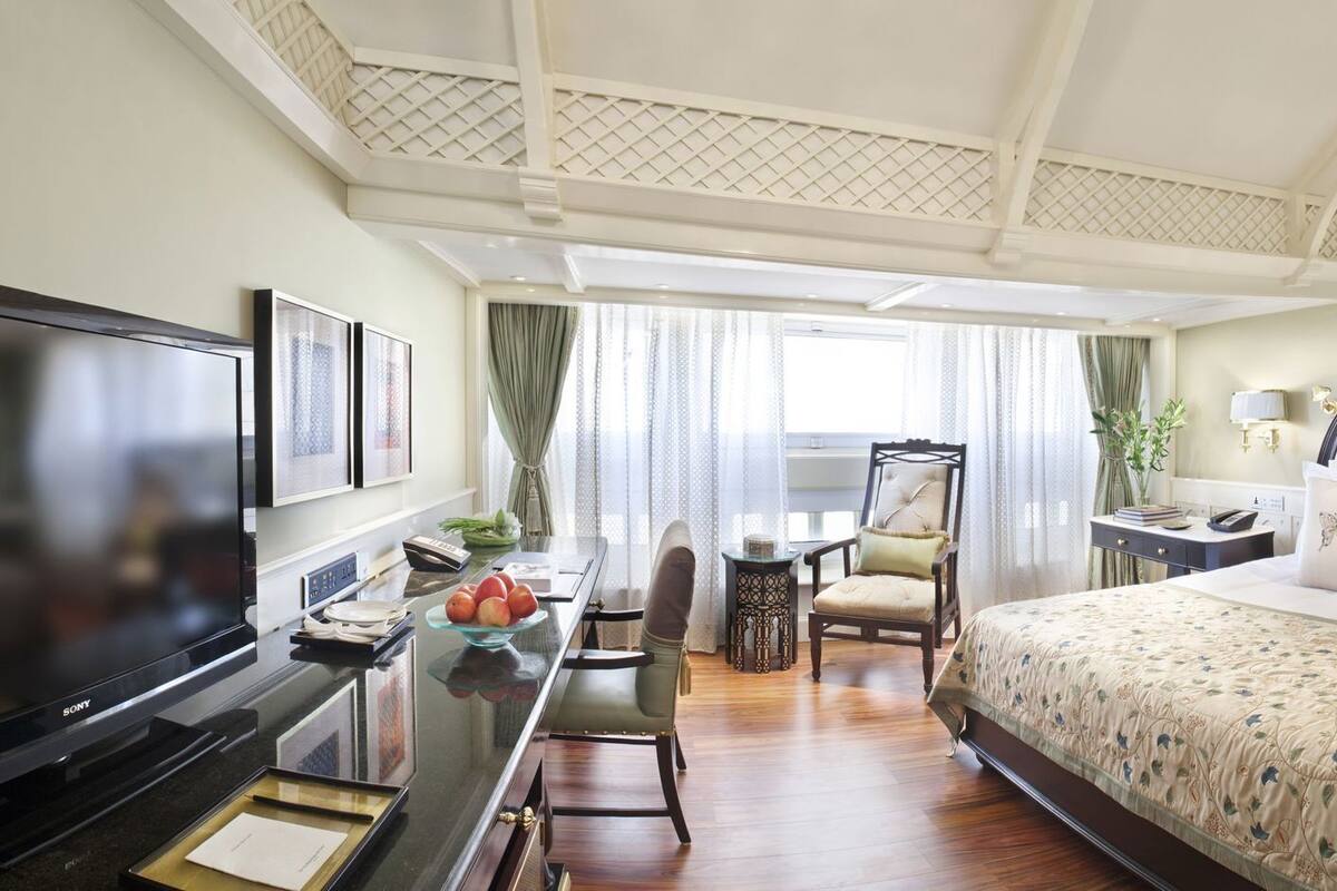 A hotel room with a bed, a desk, a TV, and a view of the outdoors.