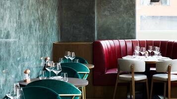 A restaurant interior with teal chairs, wooden tables, and a red booth.