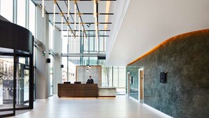 A spacious lobby with a reception desk, large windows, and a modern ceiling design. - Hyatt House Manchester - Aparthotel (Manchester)