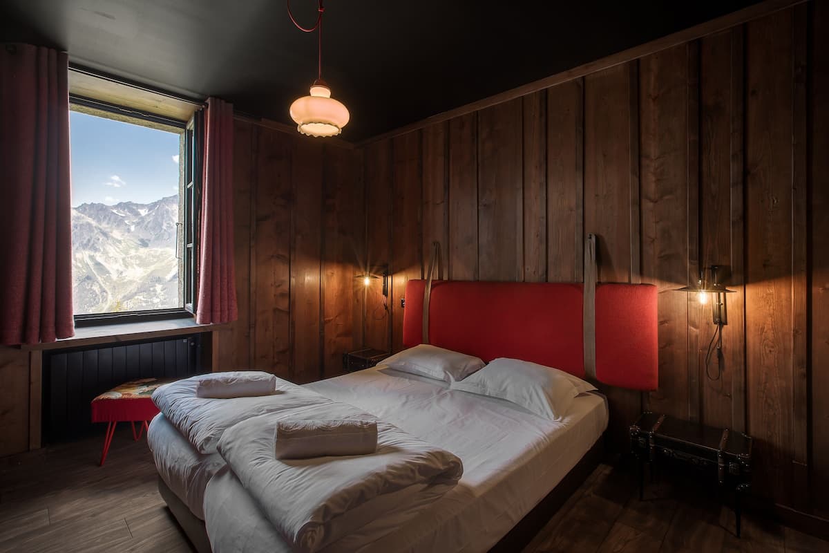 Une pièce en bois avec un lit, une fenêtre et une tête de lit rouge.