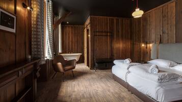 Una habitación con paneles de madera, con una cama, una silla, un lavamanos y una chimenea.
