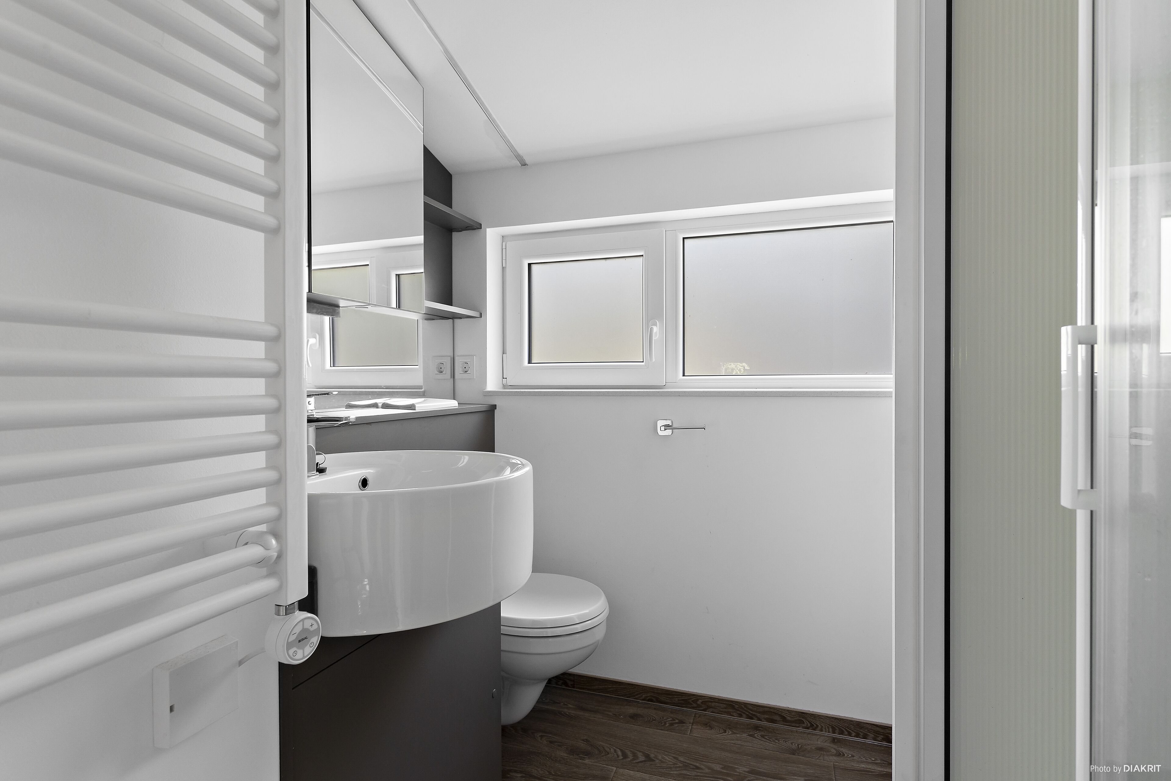 A modern bathroom with a toilet, sink, and mirror.