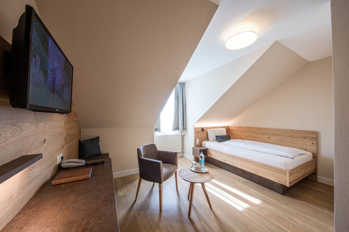 Una habitación de hotel moderna con una cama de madera, un escritorio, una silla y una televisión.