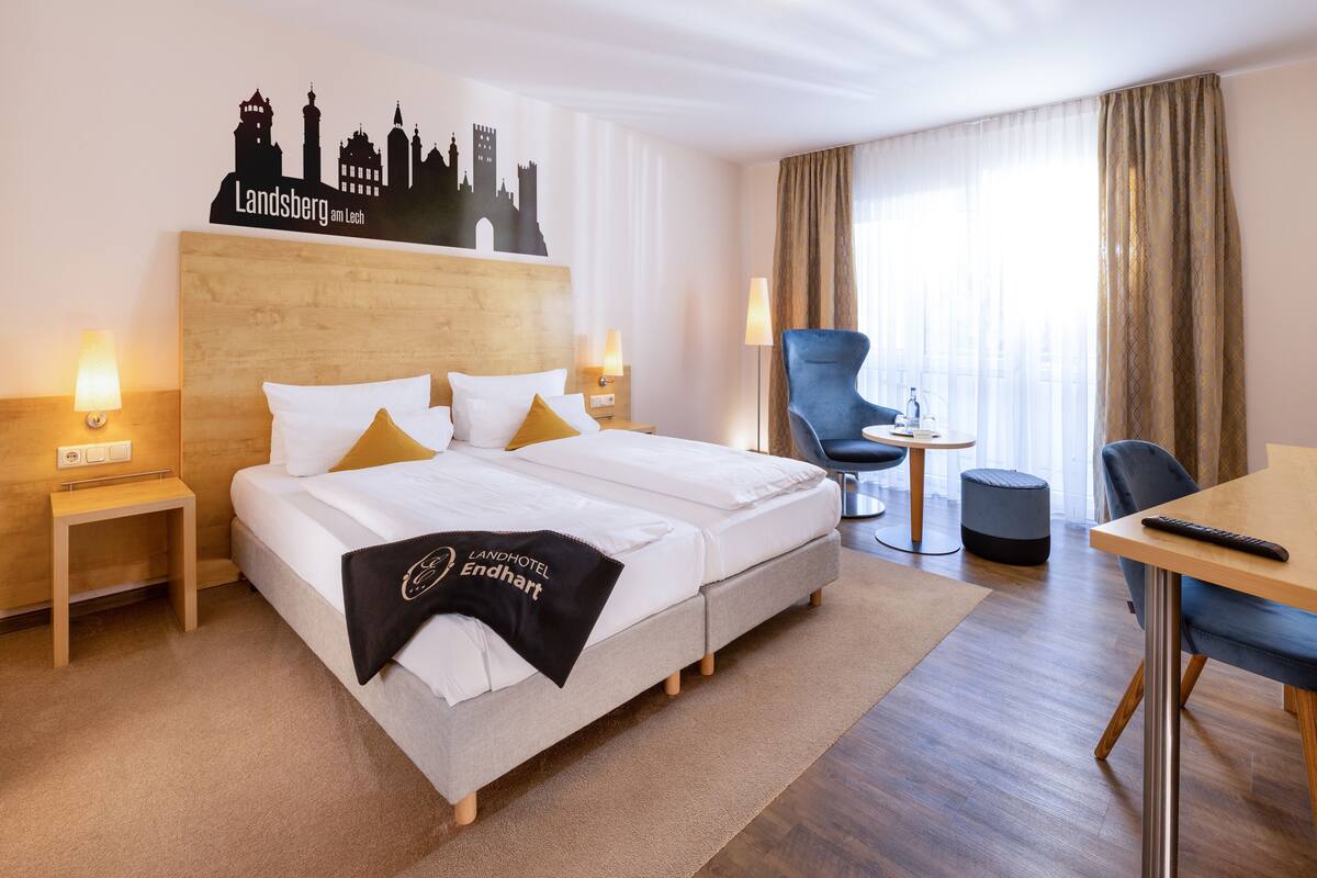 Una habitación de hotel con una cama, una silla, una mesa y una lámpara.