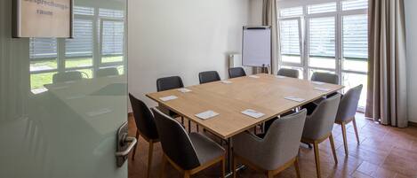 A conference room with a long table, chairs, a projector, and a whiteboard.