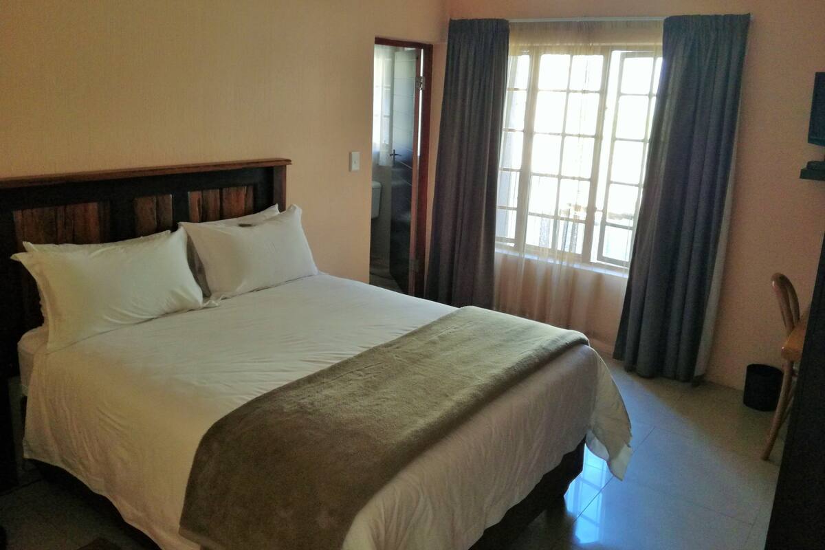 A bed with a wooden headboard, white bedding, and a beige throw blanket.