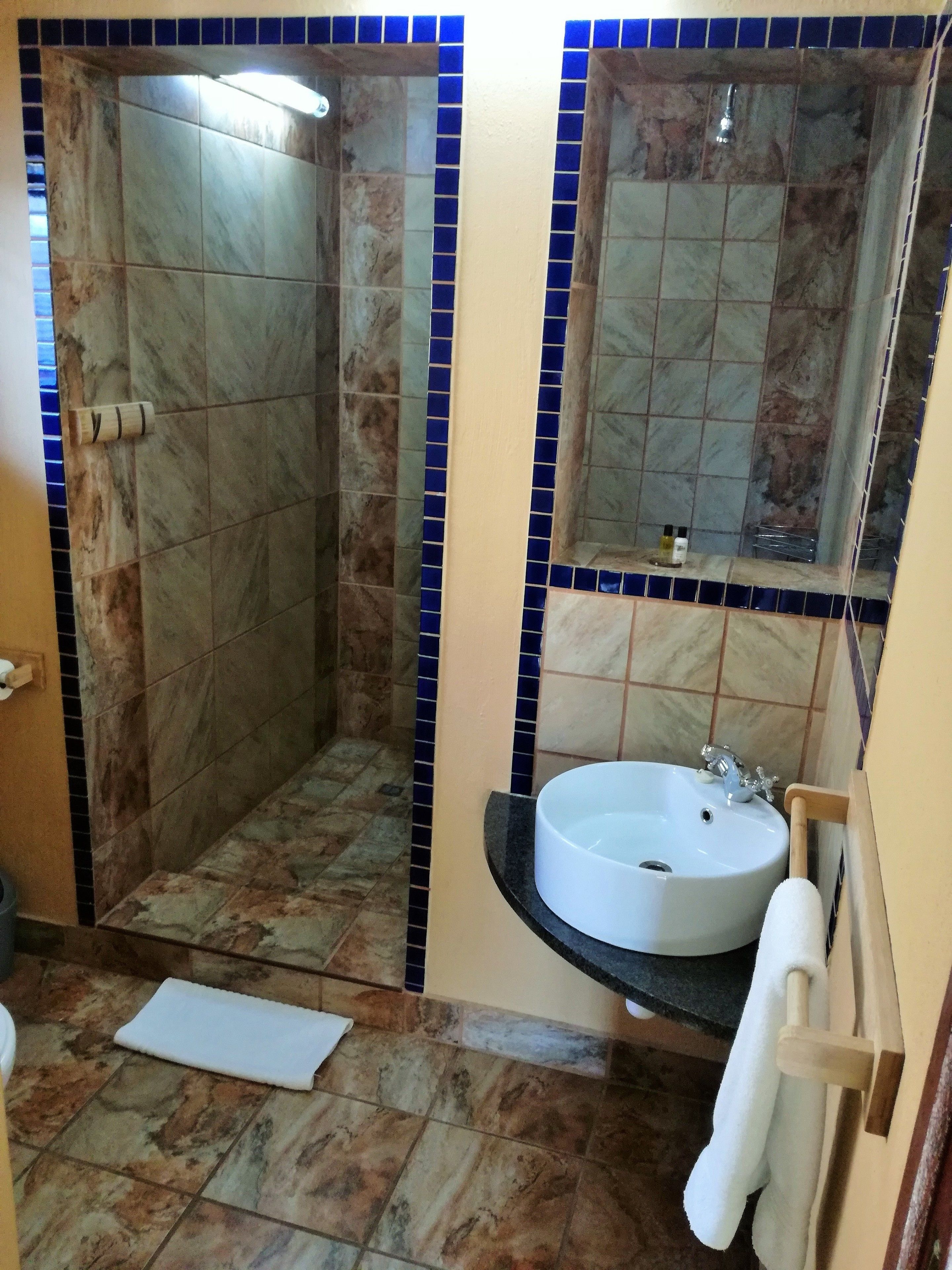 A bathroom with a shower, sink, and mirror.