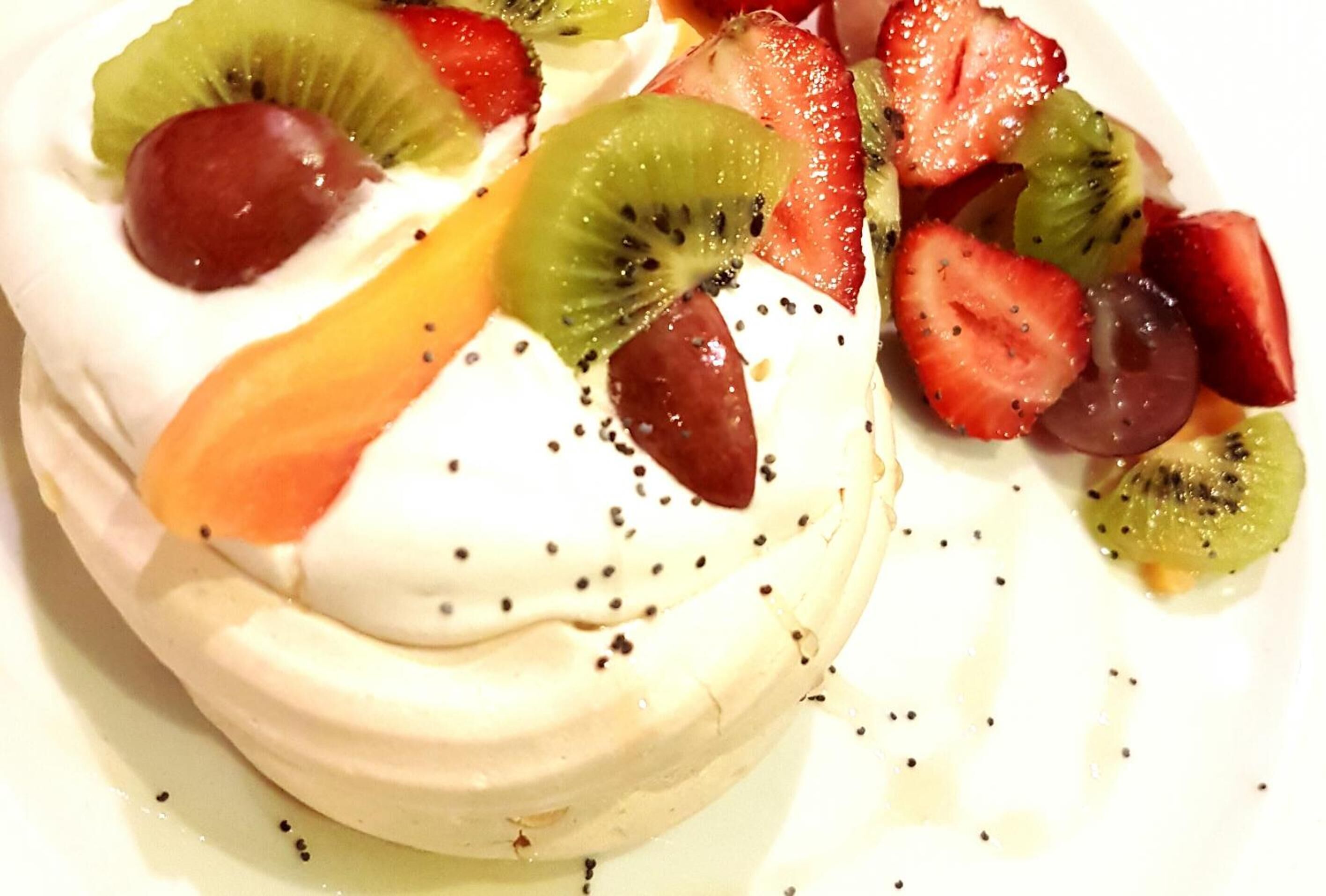 A dessert with meringue, kiwi, strawberries, and grapes.