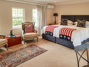 Une chambre à coucher avec un grand lit, une chaise, une table de chevet et un tapis.
