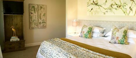 Quarto bem organizado com cama, duas mesas de cabeceira, um criado-mudo, um abajur e um quadro na parede.