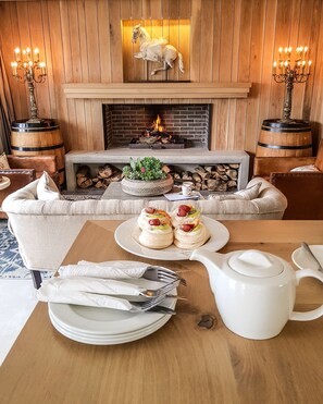 Un coin repas chaleureux avec une cheminée, un mur en bois et une sculpture équestre décorative au-dessus.