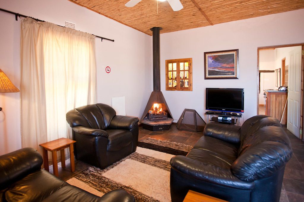 Una sala de estar con sofás de cuero, chimenea, televisor y ventilador de techo.