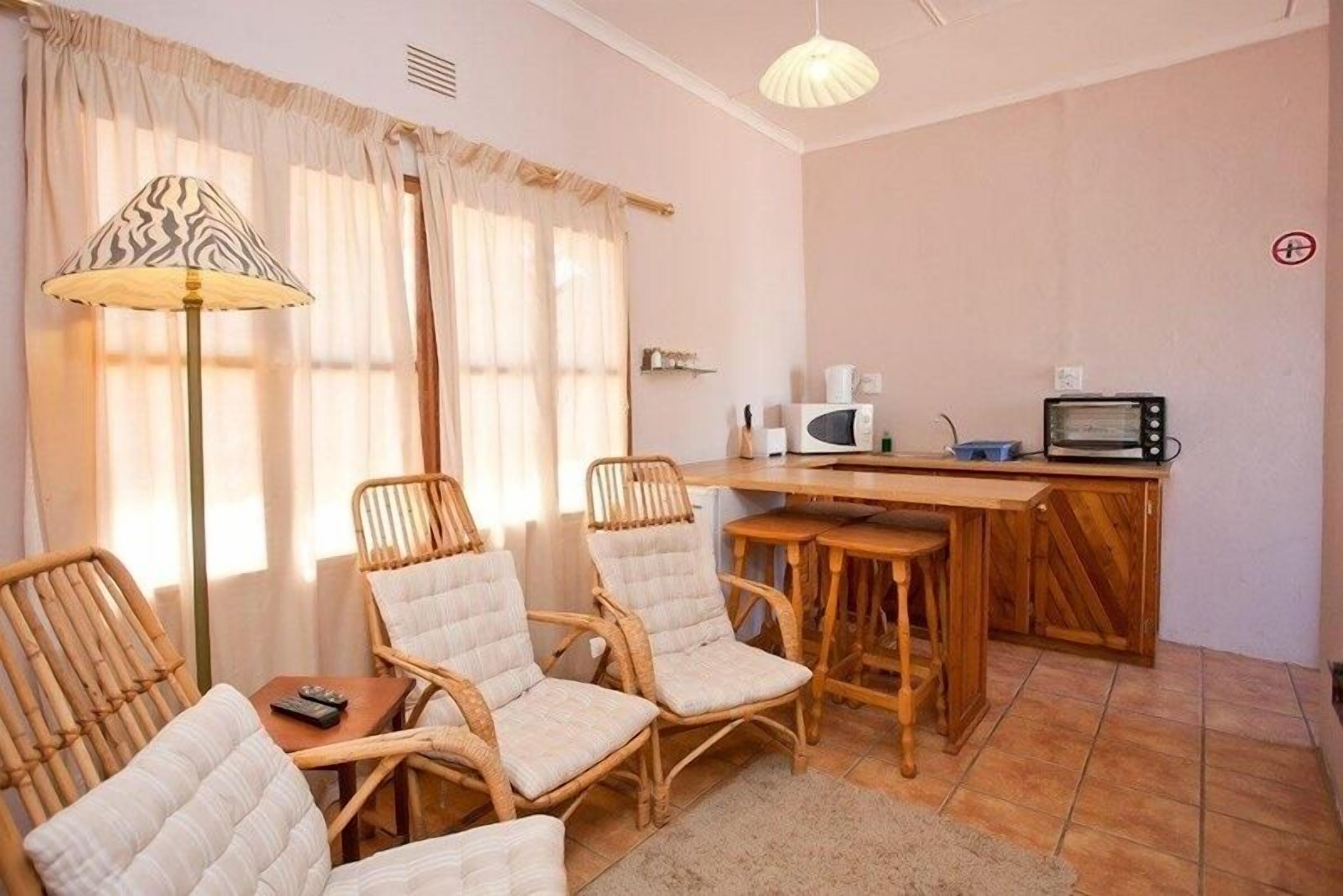 Une pièce confortable avec des fauteuils en osier, une petite table à manger, un four à micro-ondes et un grille-pain.