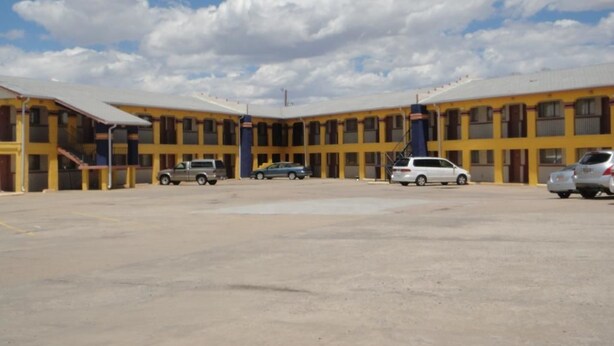 A motel with a central courtyard, multiple parking spaces, and a clear blue sky. - Econo Lodge Las Vegas NM (Las Vegas)