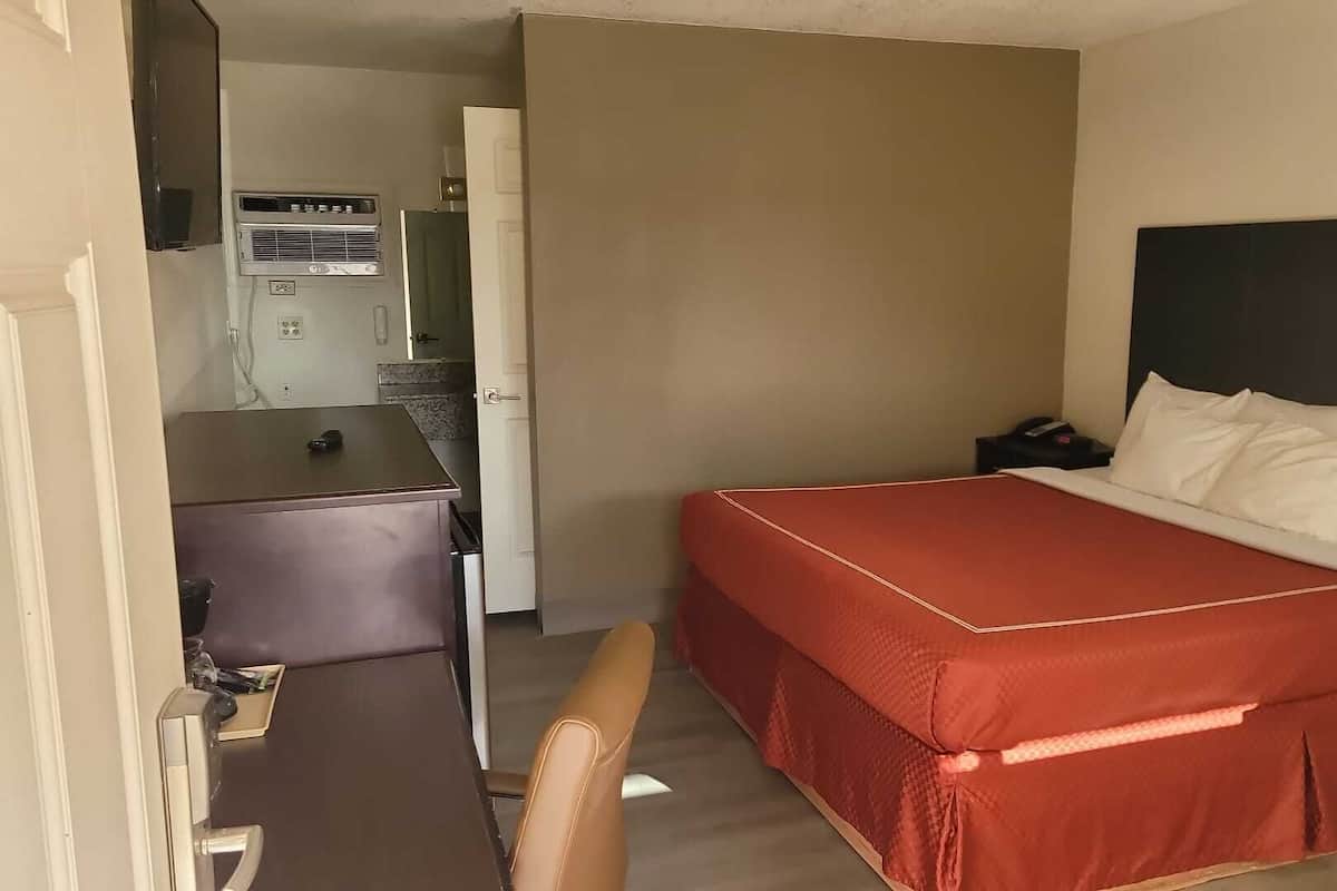 Une chambre d’hôtel avec un lit, un bureau et une kitchenette.