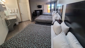 A hotel room with two beds, a desk, a TV, and a bathroom with a sink and towel rack. - Econo Lodge Las Vegas NM (Las Vegas)