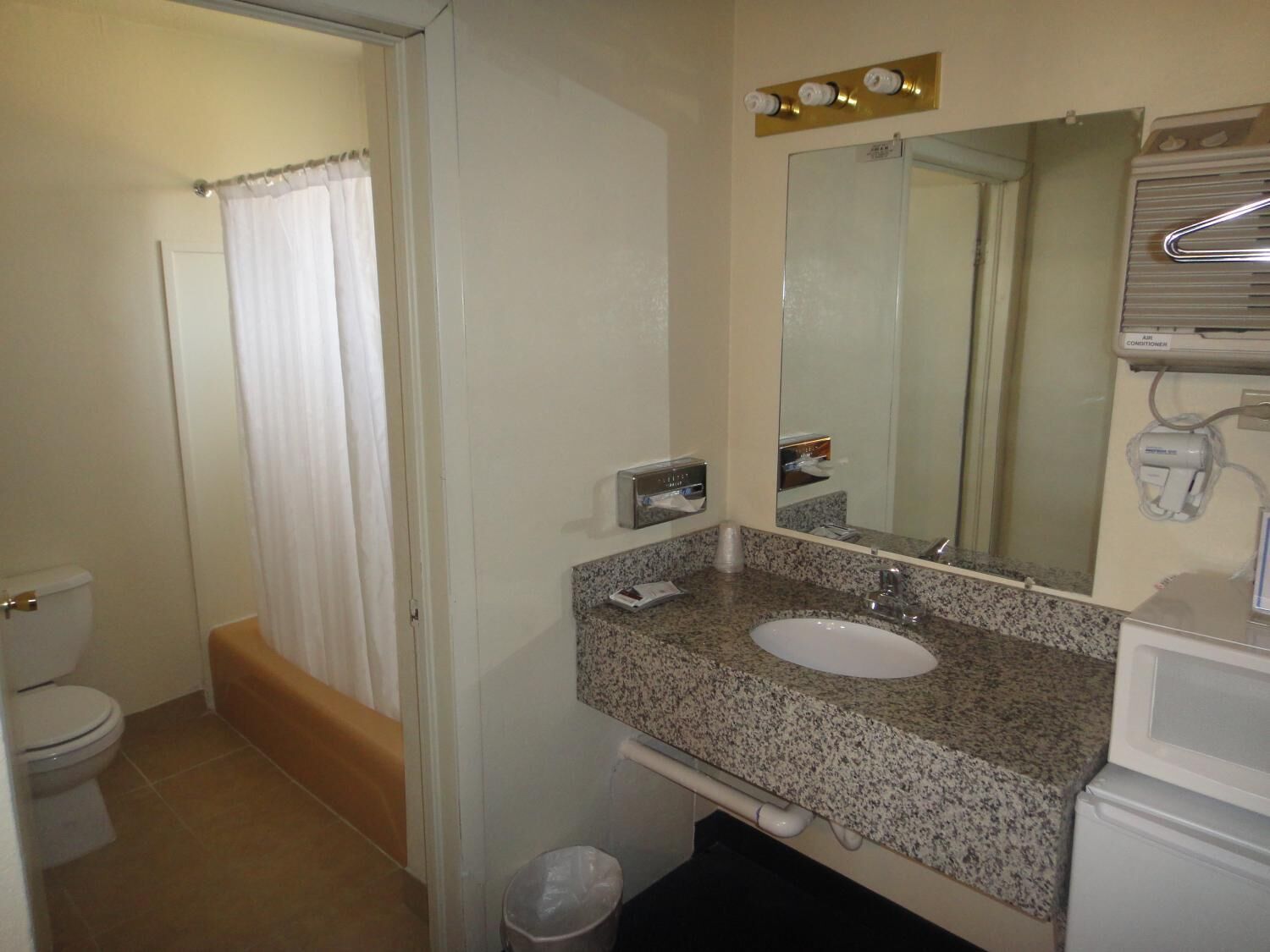 Une salle de bain équipée de toilettes, d’un lavabo, d’un miroir et d’un rideau de douche.