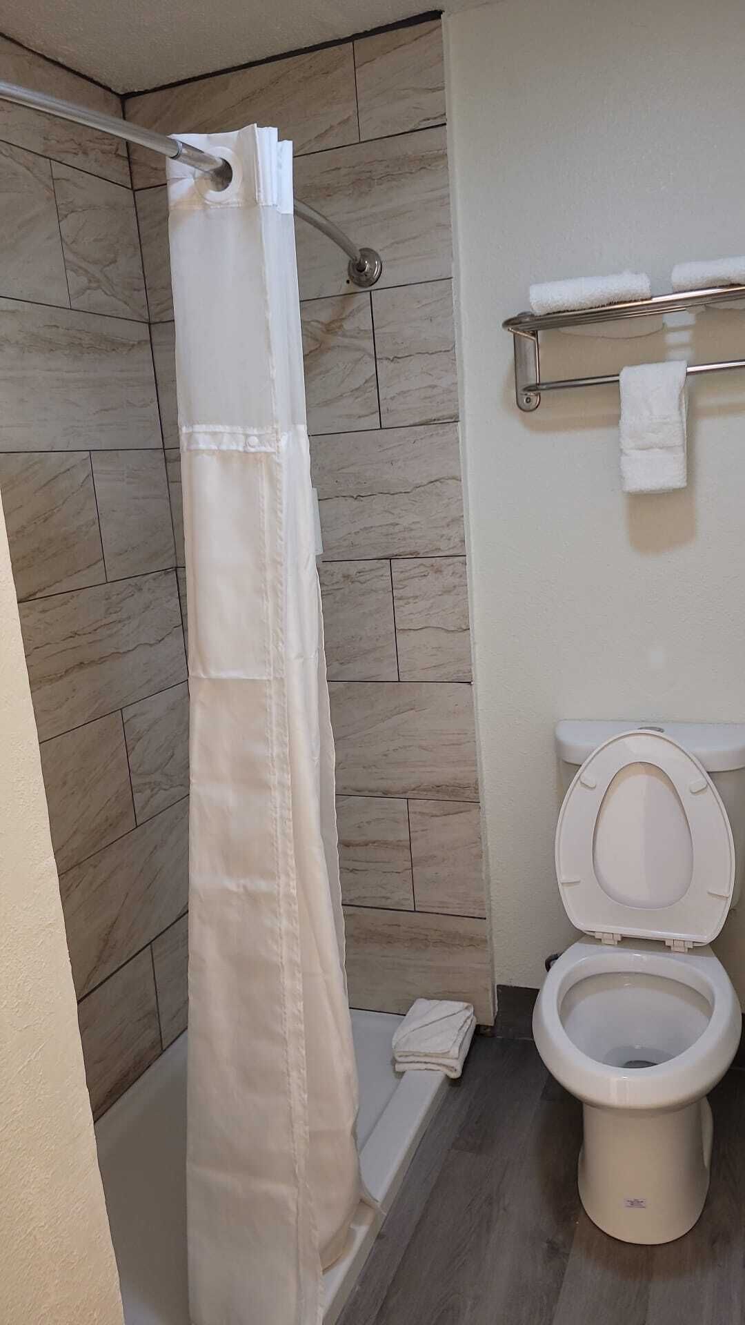 A bathroom with a shower curtain, a toilet, and a towel rack.