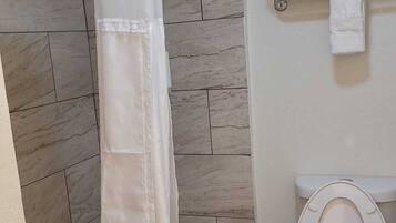 A bathroom with a shower curtain, a toilet, and a towel rack.