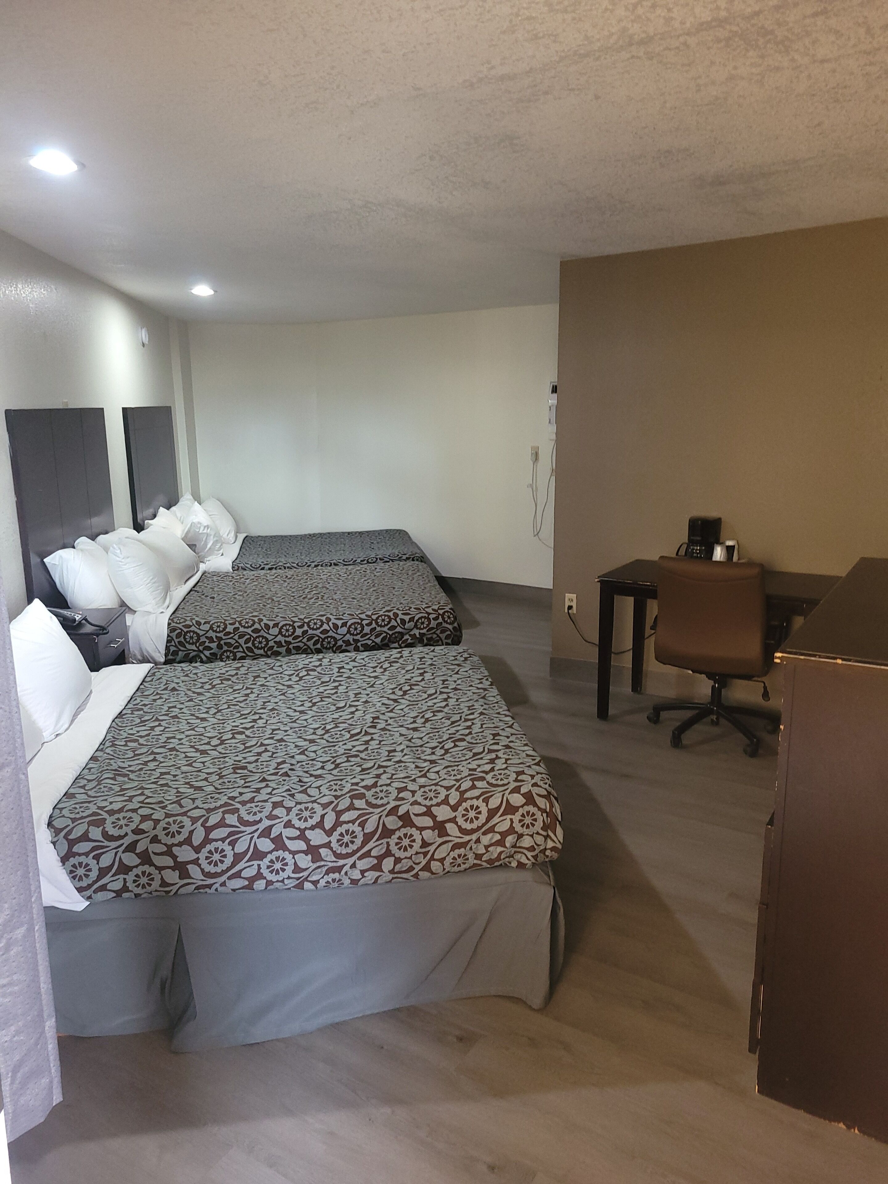 Une chambre d’hôtel avec deux lits, un bureau et une chaise.