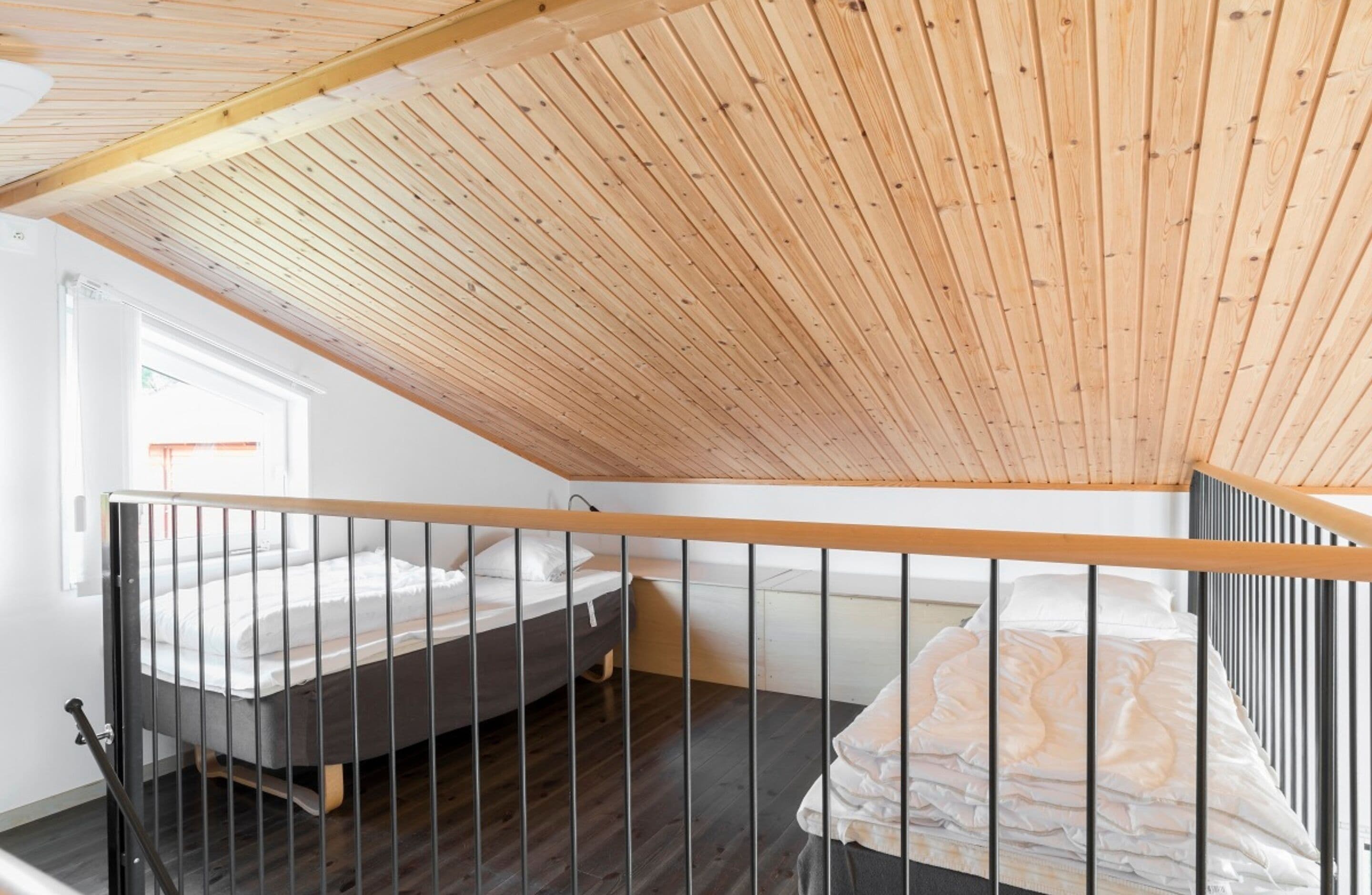 Ein Schlafzimmer mit schrägem Dach, einem Bett und einem Fenster.