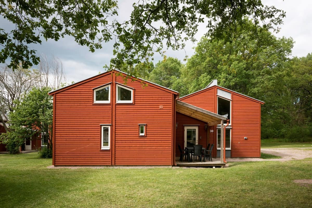 A red wooden house with a porch and a small patio area.