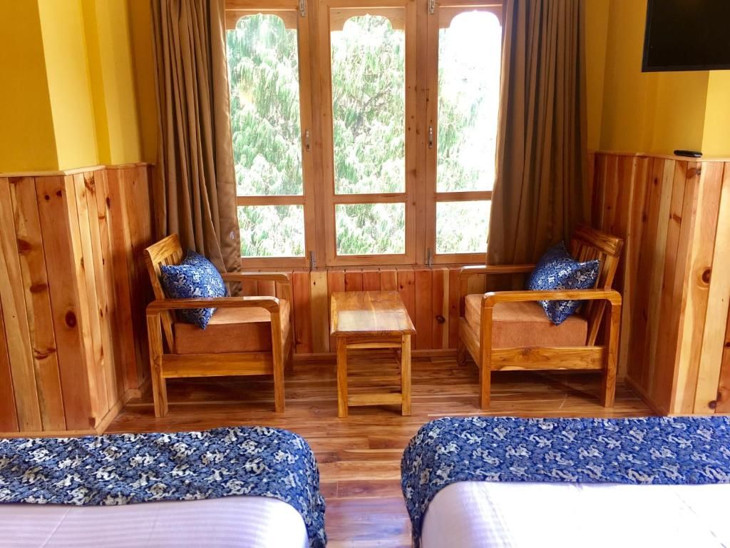 A room with two beds, a wooden table, and two chairs.