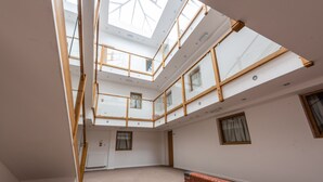 A multi-level interior with a skylight, wooden beams, and a brick wall. - Quarterz (Chester)