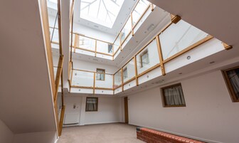A multi-level interior with a skylight, wooden beams, and a brick wall.