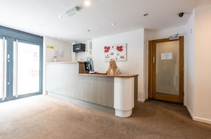 A reception area with a counter, a coffee machine, a microwave, and a door with a sign.