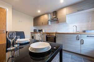 A modern kitchen with a black countertop, stainless steel appliances, and wooden cabinets.