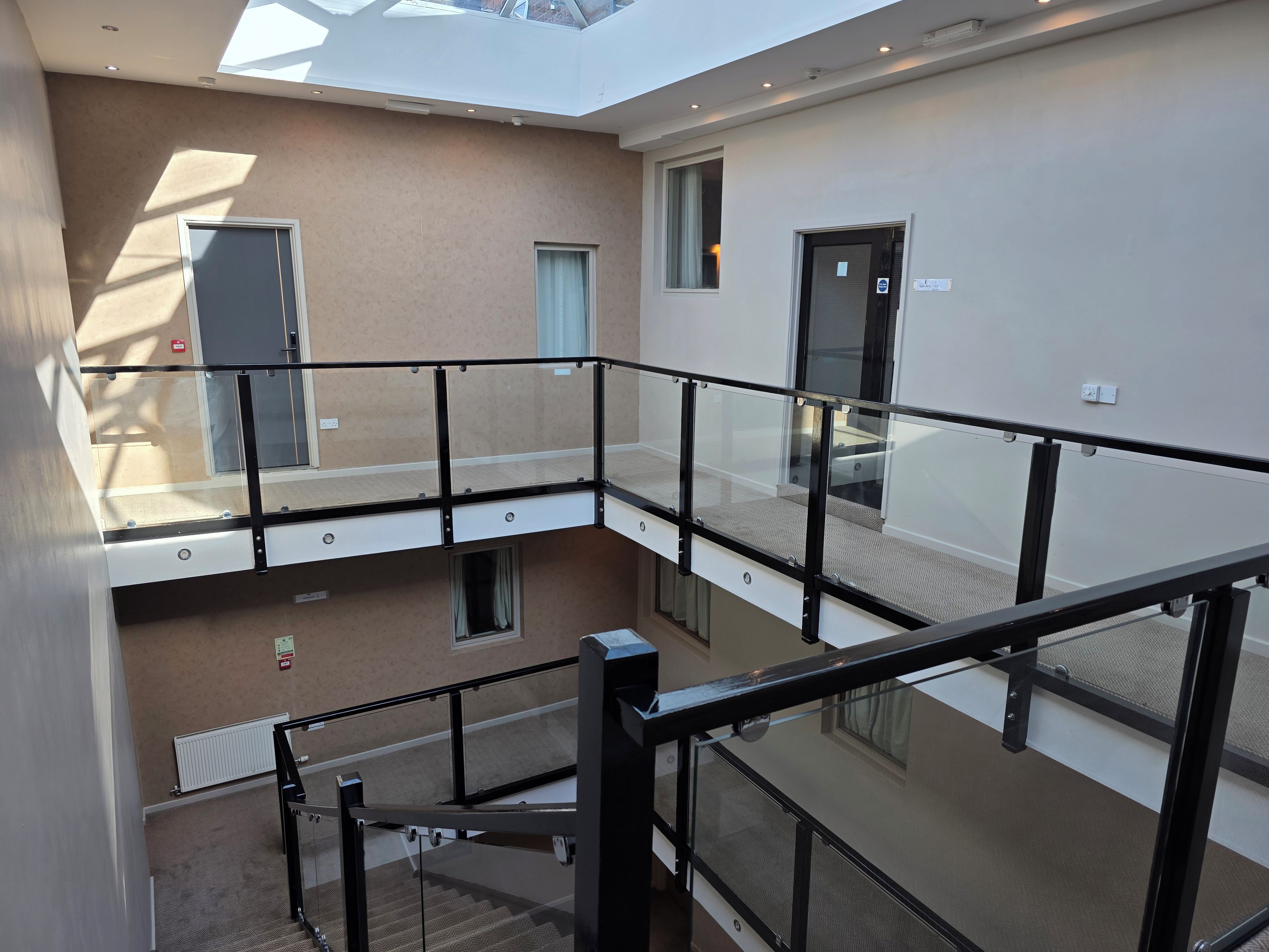 Un intérieur à plusieurs niveaux, doté de rampes en verre, d’un escalier et d’une verrière.