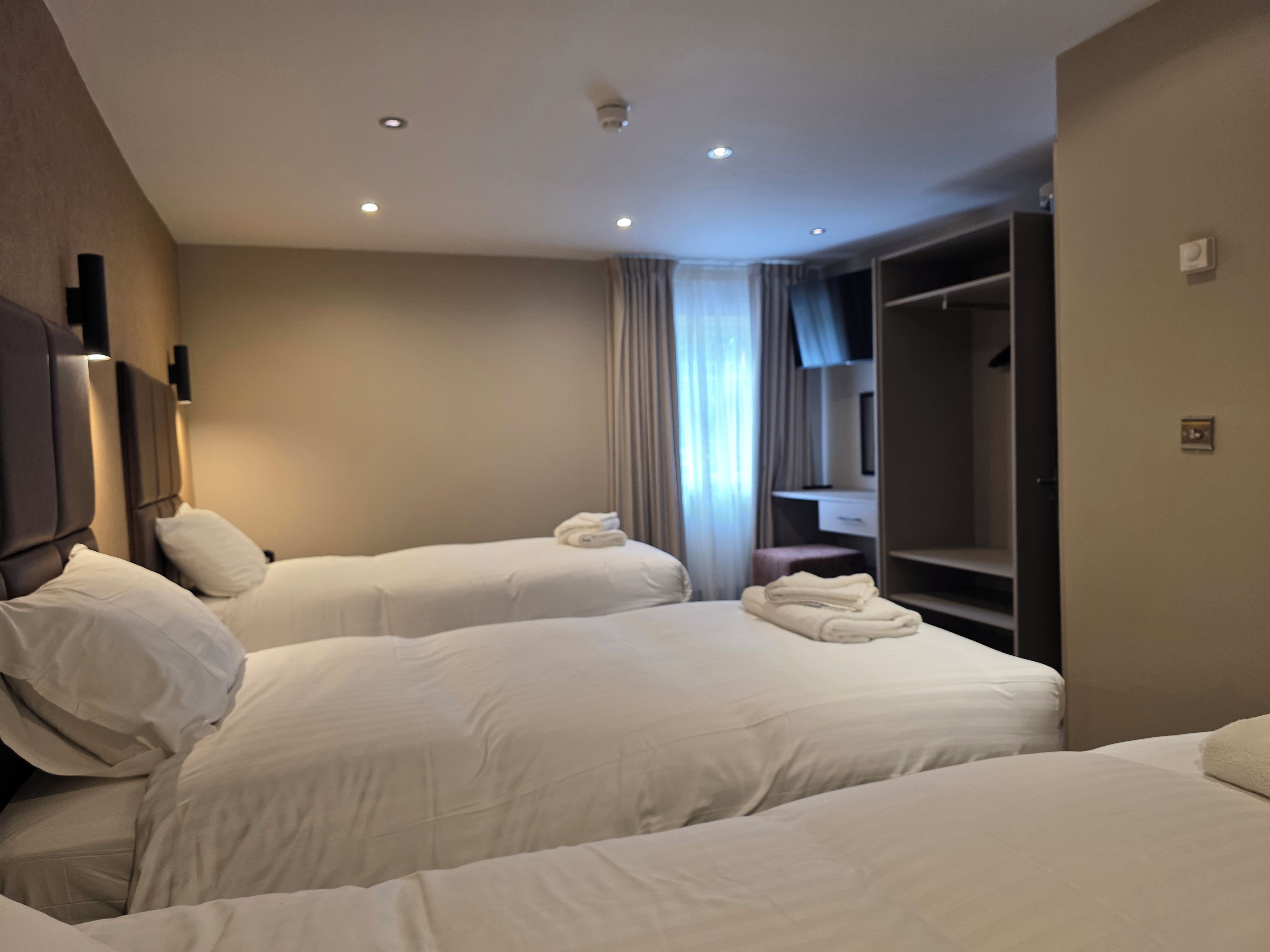 Une chambre d’hôtel avec deux lits, une armoire, un bureau et un miroir.