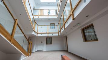 A spacious atrium with a high ceiling, skylights, and a central staircase.