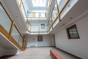 A spacious atrium with a high ceiling, skylights, and a central staircase.