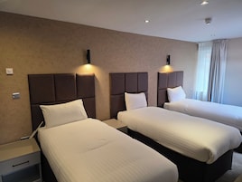 Una habitación de hotel con dos camas, cada una con cabecera y mesitas de noche.