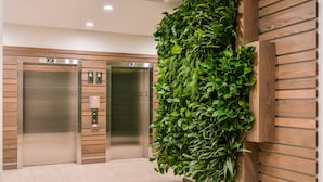 An elevator area with two elevators, wooden paneling, and a vertical garden wall. - Courtyard by Marriott Eugene Downtown (Eugene)