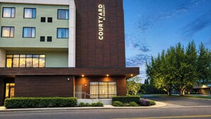 A Courtyard by Marriott hotel with a modern design, featuring a two-story structure, a well-lit entrance, and a landscaped front yard. - Courtyard by Marriott Eugene Downtown (Eugene)