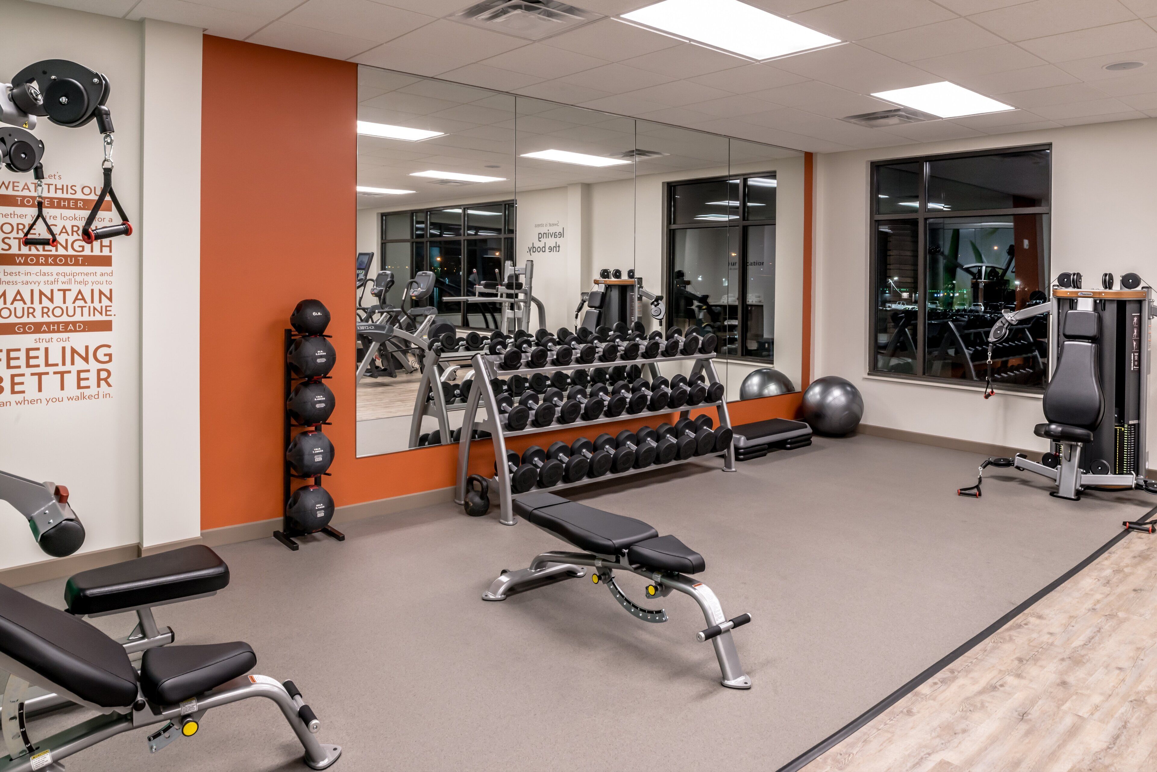 A gym with weightlifting equipment, dumbbells, and exercise machines.