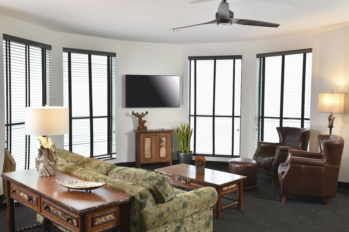 Una sala de estar con sofá, sillones, una mesa de centro, televisor y ventilador de techo.